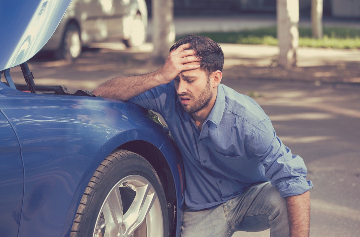 man frustrated leaning on car